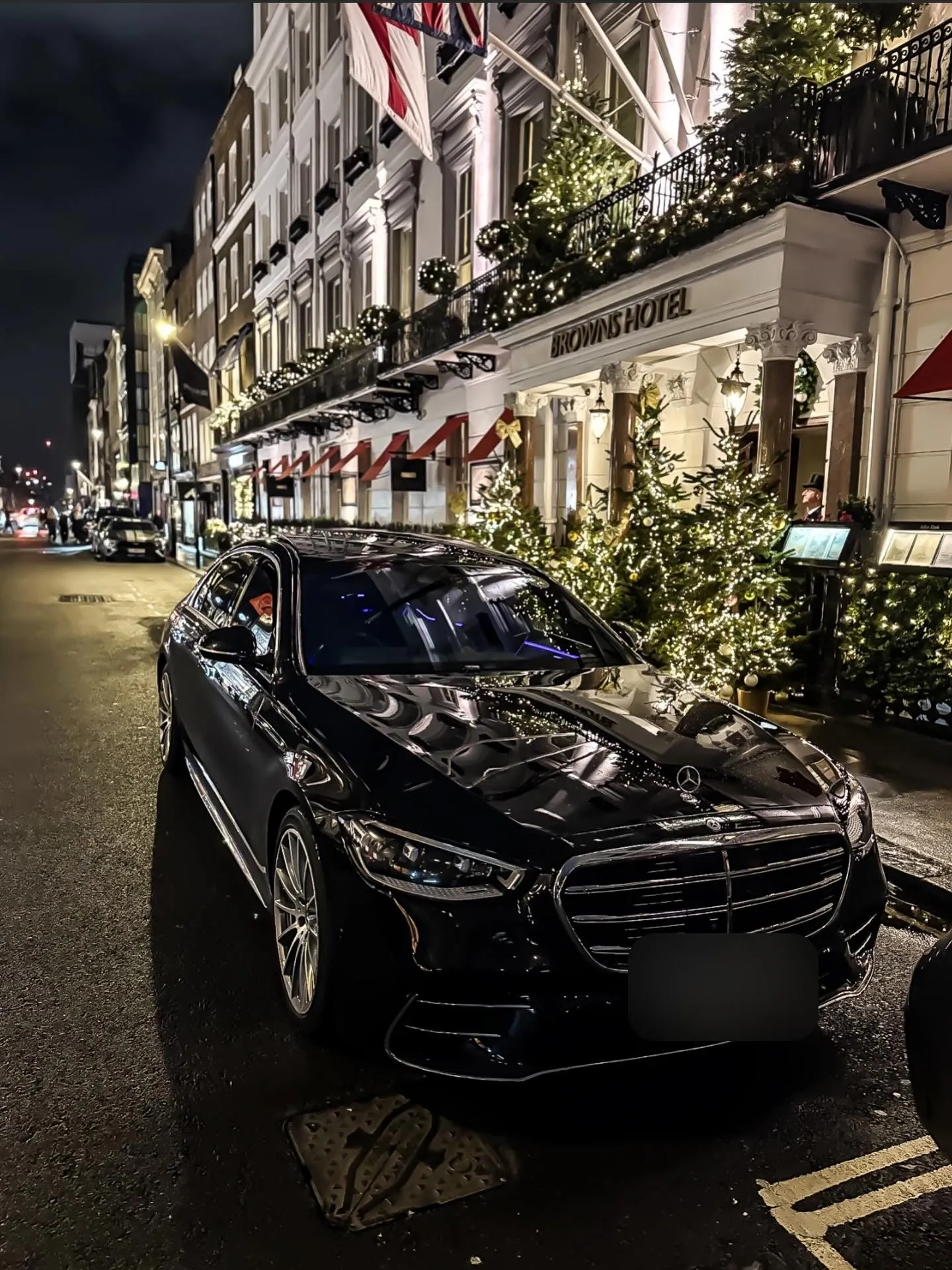 Black Mercedes S-Class outside Brown's Hotel in Mayfair, London, at night with the Christmas lights on