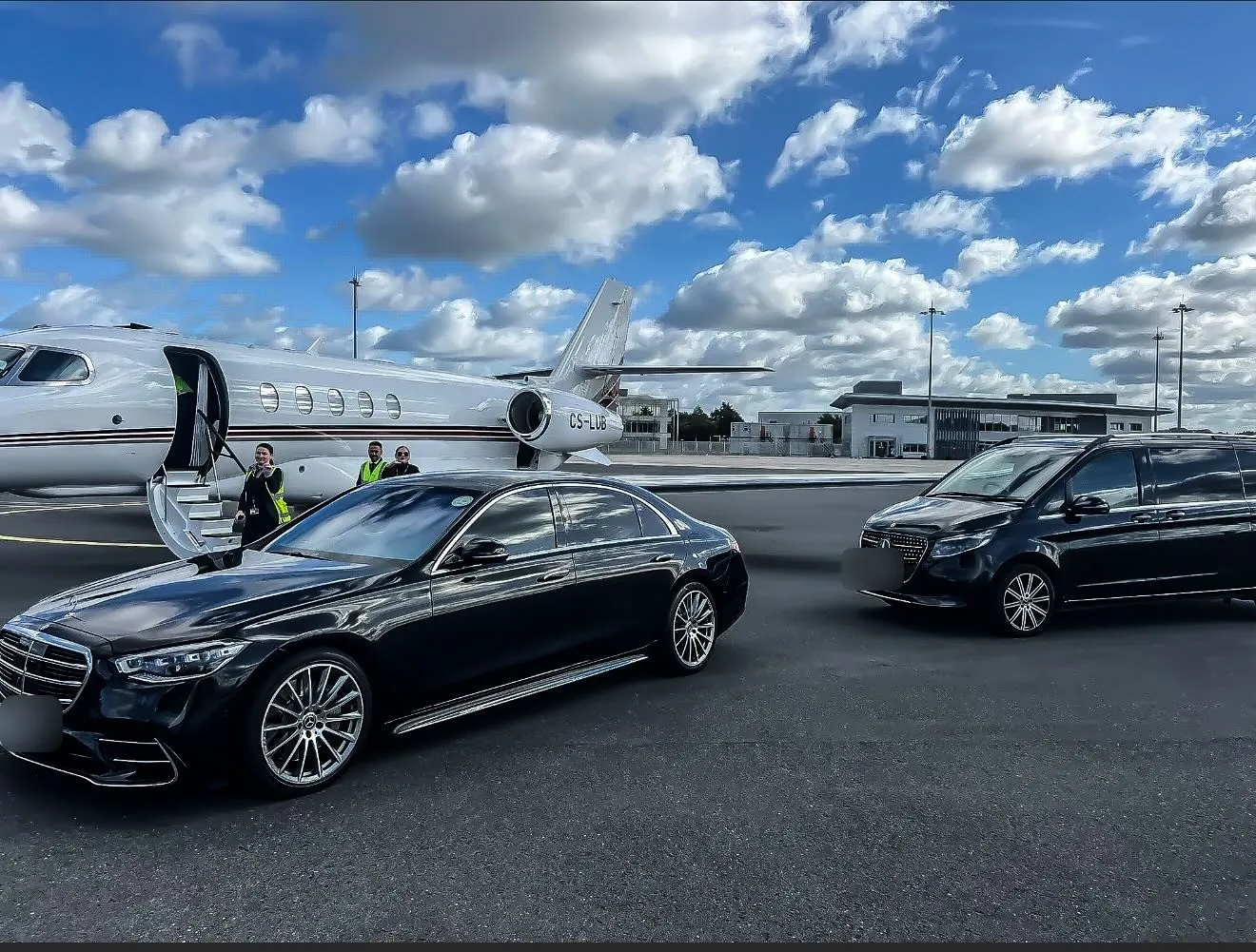 Black Mercedes S-Class and V-Class parked beside a private jet on an airfield